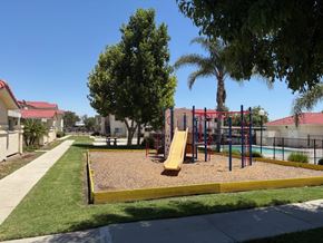 Perris apartment for rent - A playground with a yellow slide and a red and blue swing set.