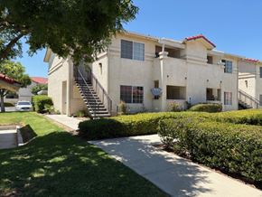 Perris apartment for rent - A white building with a red roof and a tree in front.