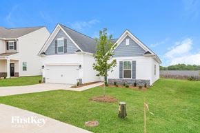 Greenville house for rent - A house with a white and grey exterior is shown with a tree in the front yard.