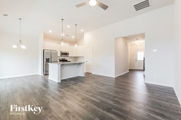 Greenville house for rent - A spacious kitchen and living room with wooden flooring and a ceiling fan.