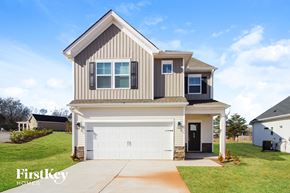 Greenville house for rent - a beige and brown house with a white garage door