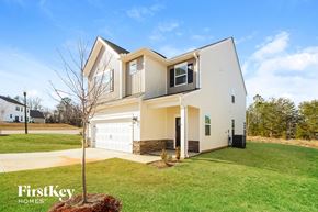 Greenville house for rent - a white house with a white garage door and a green lawn