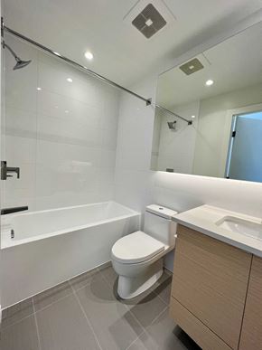 Vancouver apartment for rent - A white toilet sits next to a sink in a modern bathroom.