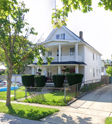 Cleveland apartment for rent - A white house with a porch and a tree in front.