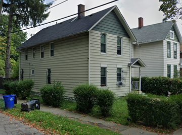 Cleveland apartment for rent - A house with a grey siding and a dark roof with a chimney.