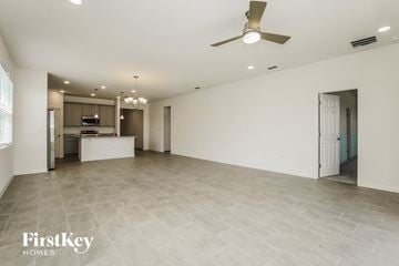 Kissimmee house for rent - A spacious room with a ceiling fan and a kitchen area in the background.
