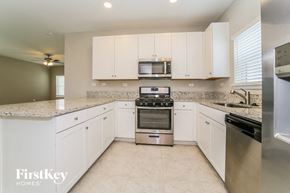 Yulee house for rent - a kitchen with white cabinets and granite counter tops and stainless steel appliances