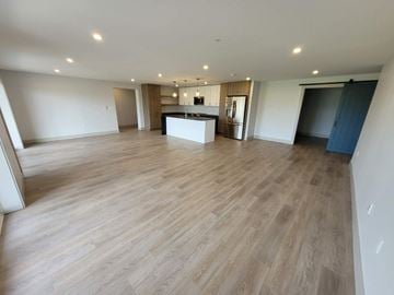 Bedford apartment for rent - A spacious room with wooden flooring and a kitchen area in the background.