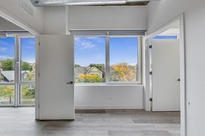 Chicago apartment for rent - A room with white walls and a large window with a view of houses and trees outside.