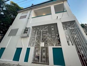 San Juan apartment for rent - A white building with a blue stripe and a window with a decorative iron grill.