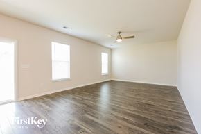 Greenville house for rent - A spacious room with wooden floors and a ceiling fan.