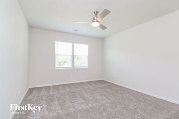 Simpsonville house for rent - a spacious living room with carpet and a ceiling fan