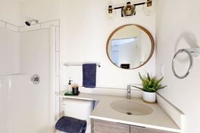 Edmonton apartment for rent - A bathroom with a white sink and a round mirror.