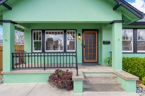 Sacramento house for rent - the front of a green house with a porch and a brown door