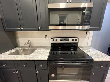 Philadelphia apartment for rent - a kitchen with black cabinets and a stove and a sink