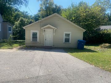 Collinsville apartment for rent - a small tan house with a driveway and a blue trash can