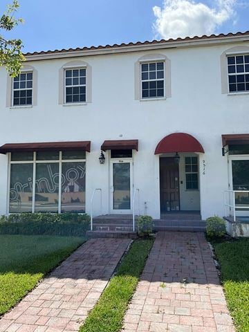 Miami apartment for rent - A white building with a red awning and a glass door.
