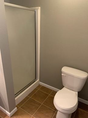 Dodge City apartment for rent - A white toilet in a bathroom with a glass door shower.