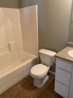 Dodge City apartment for rent - A white toilet sits next to a bathtub in a bathroom.