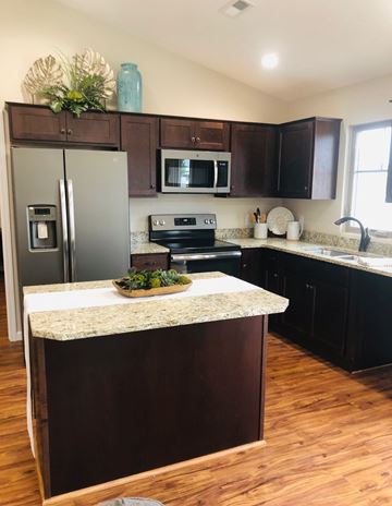 Dodge City apartment for rent - A kitchen with a refrigerator, microwave, oven, sink and wooden floors.