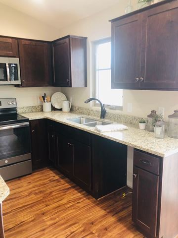 Dodge City apartment for rent - A kitchen with dark wood cabinets and a granite countertop.