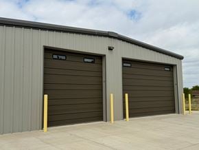 Dodge City apartment for rent - Two garage doors are closed and have yellow posts in front of them.