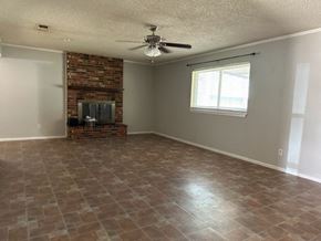 Snyder house for rent - an empty living room with a brick fireplace and a ceiling fan