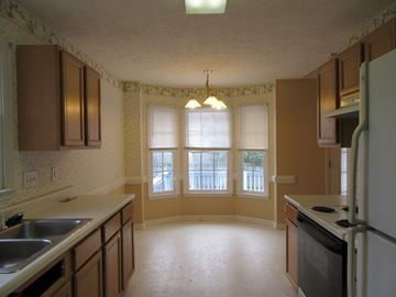 Fayetteville house for rent - A kitchen with brown cabinets and a white refrigerator.