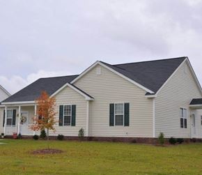 Goldsboro apartment for rent - A house with a grey roof and white siding with green shutters.