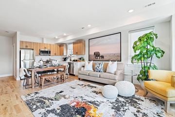 Newark apartment for rent - A living room with a rug, a yellow chair, a couch, a dining table and a painting on the wall.