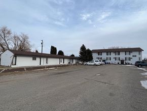 Dilworth apartment for rent - A parking lot in front of a white building with a few cars parked.