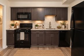 Reisterstown apartment for rent - A modern kitchen with dark brown cabinets and black appliances.