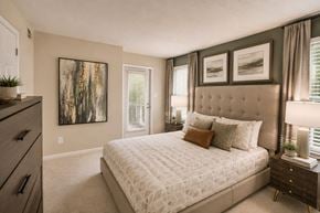 Owings Mills apartment for rent - A bedroom with a large bed, a dresser, and a painting on the wall.