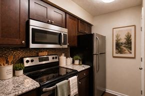 Owings Mills apartment for rent - A kitchen with a stove top oven, microwave, and refrigerator.