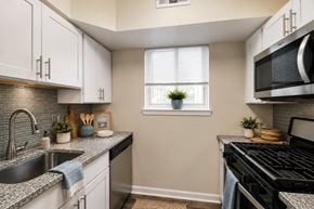 Glen Burnie apartment for rent - A kitchen with a black stove top oven and a black microwave above it.