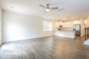 Greenville house for rent - an empty living room with a ceiling fan and a kitchen