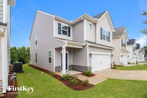 Simpsonville house for rent - a beige and white house with a driveway and a lawn