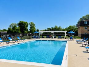 Lansdale apartment for rent - A large swimming pool with a white canopy and blue lounge chairs.