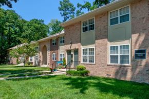 Moorestown apartment for rent - the front of a brick apartment building with grass and trees