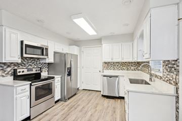 Louisville house for rent - A kitchen with white cabinets and a tile backsplash.