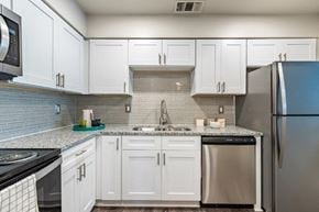 Omaha apartment for rent - a kitchen with white cabinets and stainless steel appliances