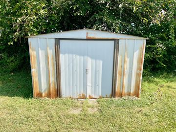 Louisville apartment for rent - A rusted metal shed sits in a grassy field.