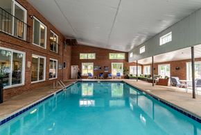 Greenville apartment for rent - A large indoor swimming pool with a tiled edge and a brick wall.