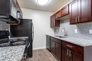 Greenville apartment for rent - A kitchen with a black stove top oven and a black microwave above it.