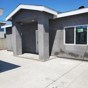 Cudahy apartment for rent - A grey building with a white roof and a window with a sign on it.