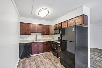 New Castle apartment for rent - A kitchen with a black refrigerator and wooden cabinets.
