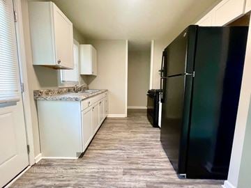 Louisville house for rent - a kitchen with white cabinets and a black refrigerator