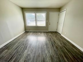 Louisville house for rent - an empty living room with vinyl flooring and a window