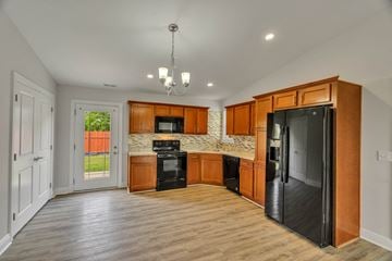 Louisville house for rent - a kitchen with wooden cabinets and a black refrigerator