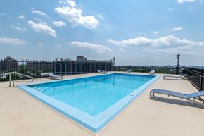 Baltimore apartment for rent - A large blue swimming pool with sun loungers and a fence around it.